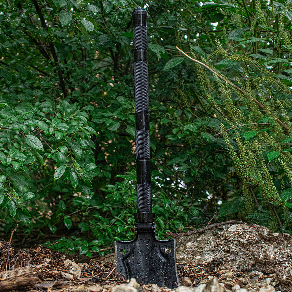 8-in-1 Survival Shovel Kit stuck in the dirt during a ligjht rain.