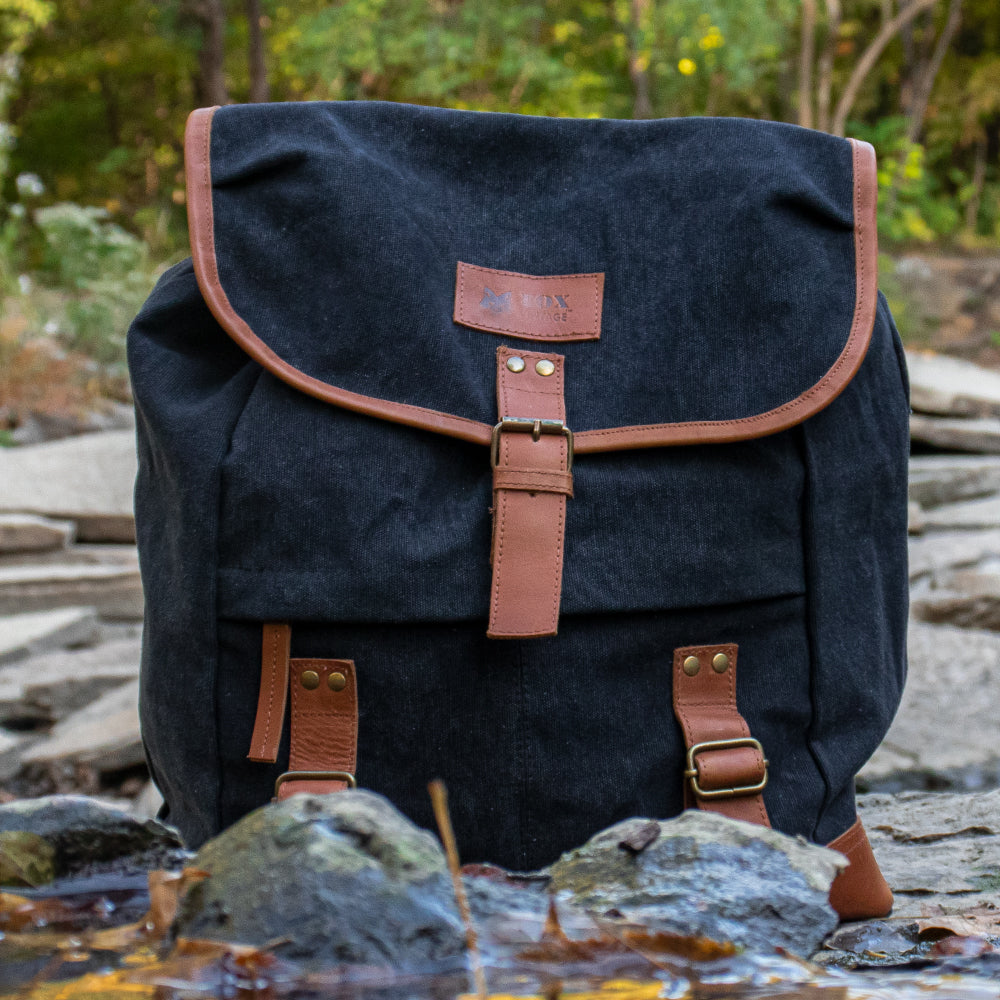 Adventurer Rucksack on top of rocks near a small river in the woods.
