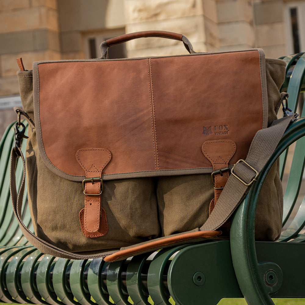 Academic Portfolio Briefcase on a green metal park bench in front of a limestone building.