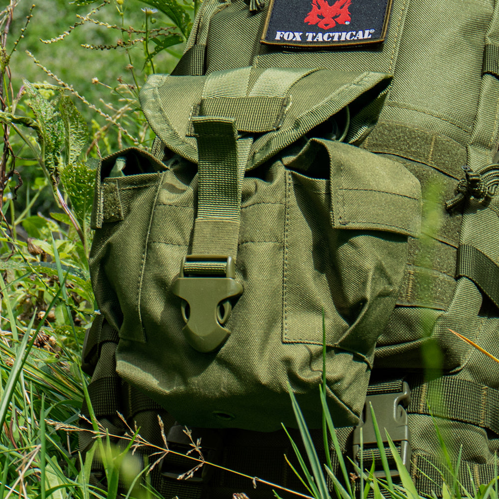 Modular 1 Quart Canteen Cover attached via modular web straps to a tactical bag laying in a sunny, grassy field.