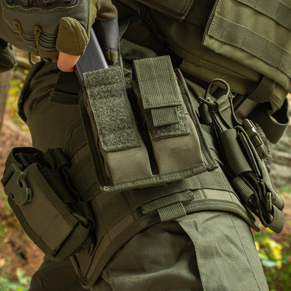 Close up of Spec Ops Drop leg on a person in the woods. The person is pulling out a pistol mag from the drop leg. 