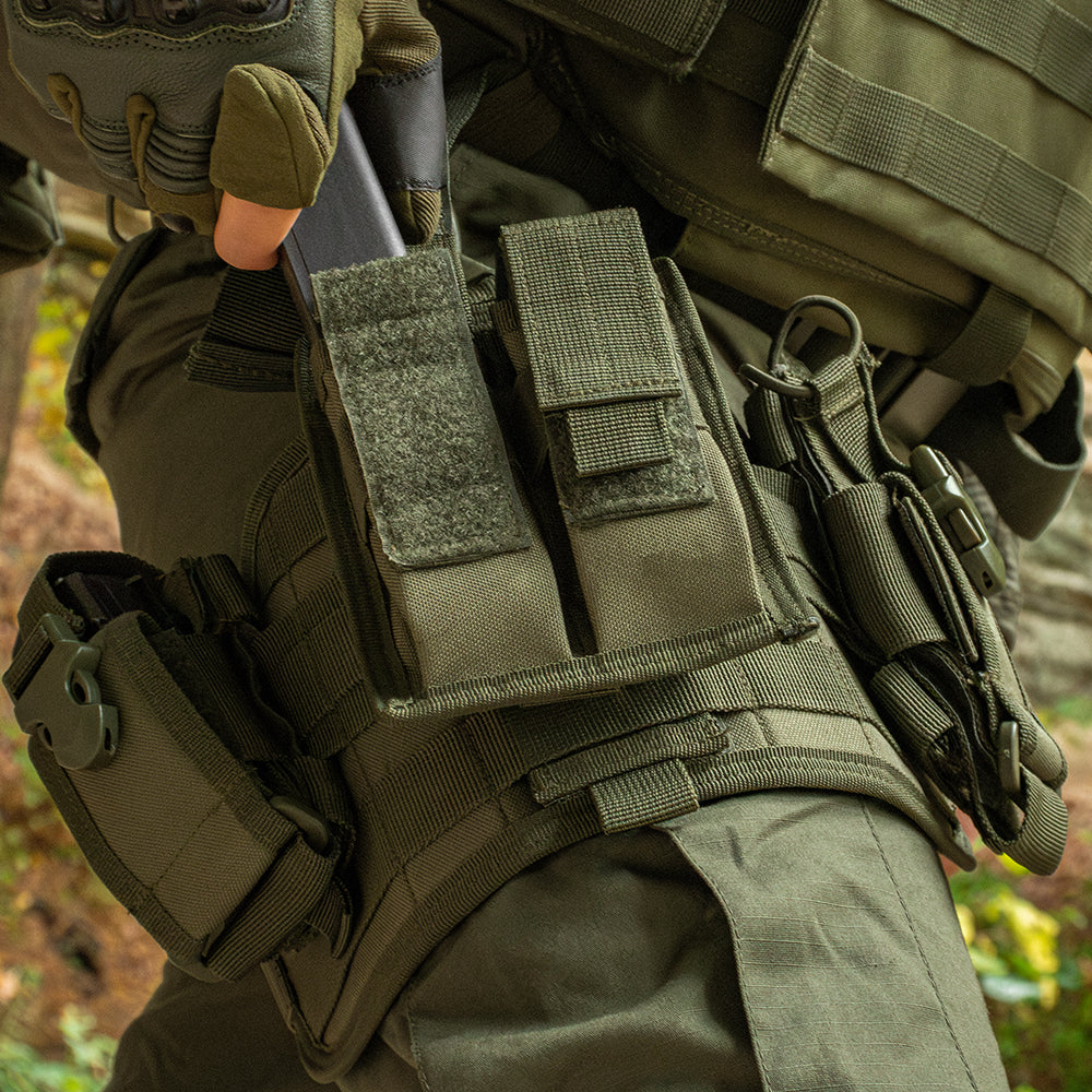 Close up of Spec Ops Drop leg on a person in the woods. The person is pulling out a pistol mag from the drop leg.
