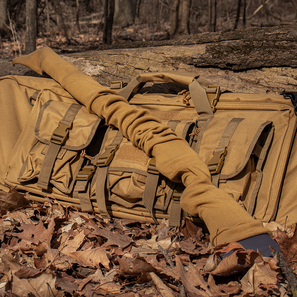 Gun sock laying on a combat case in the woods with fallen leaves surrounding it.