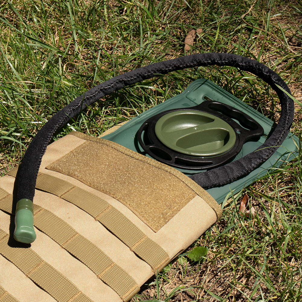 Modular Hydration Carrier laying in the grass open with a Hydration Bladder inside.