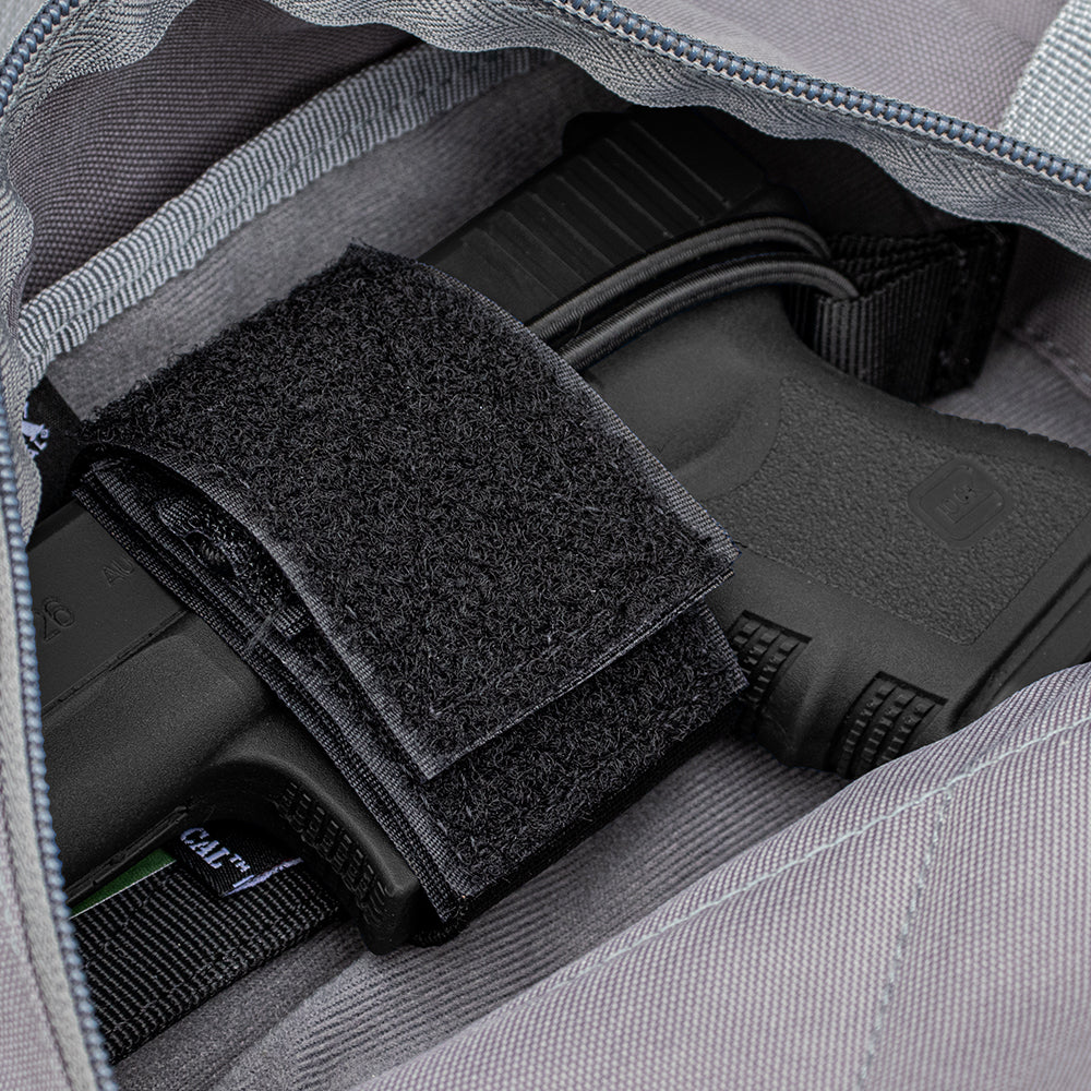 Closeup of a Universal Hook & Loop Holster with a pistol inside nestled into a hook & loop compatable compartment. 