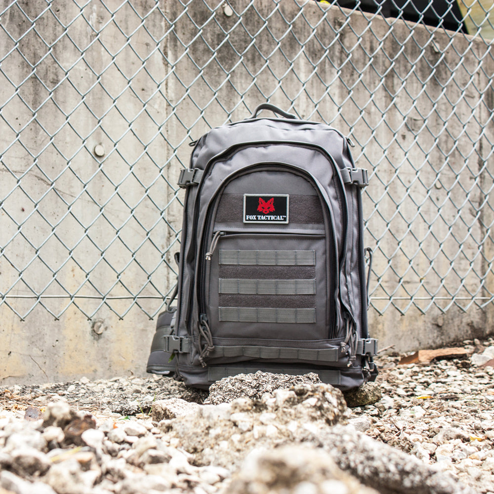 Jumbo Modular Field Pack on a rocky ground in front of a chainlink fence.