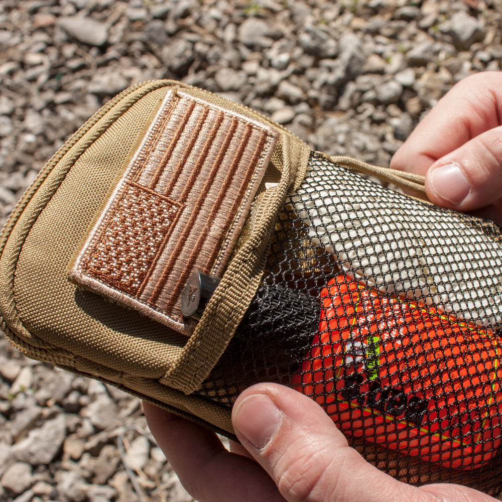 Closeup of a person holding a Tactical Wallet/Organizer with contents shown inside of the front mesh pocket.