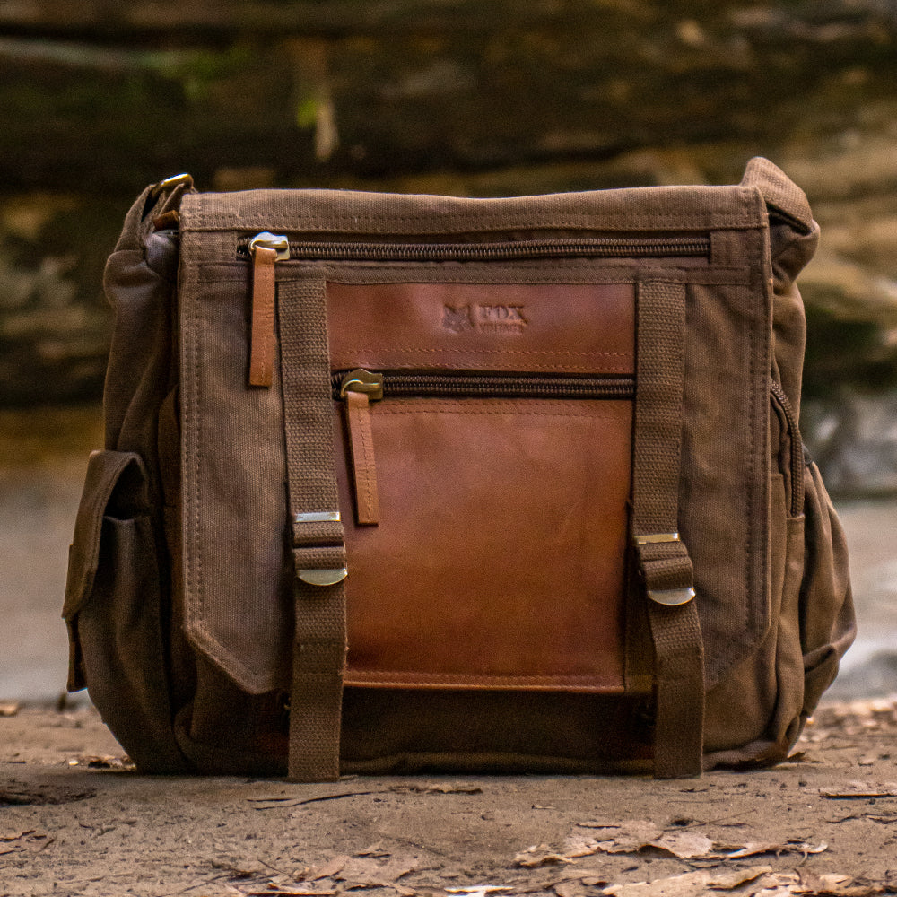 Deluxe Concealed-Carry Messenger Bag sitting in front of a small creek in a rocky valley.