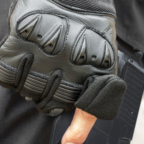Closeup of person wearing Clawed Hard Knuckle Shooter's Glove, holding a pistol. 