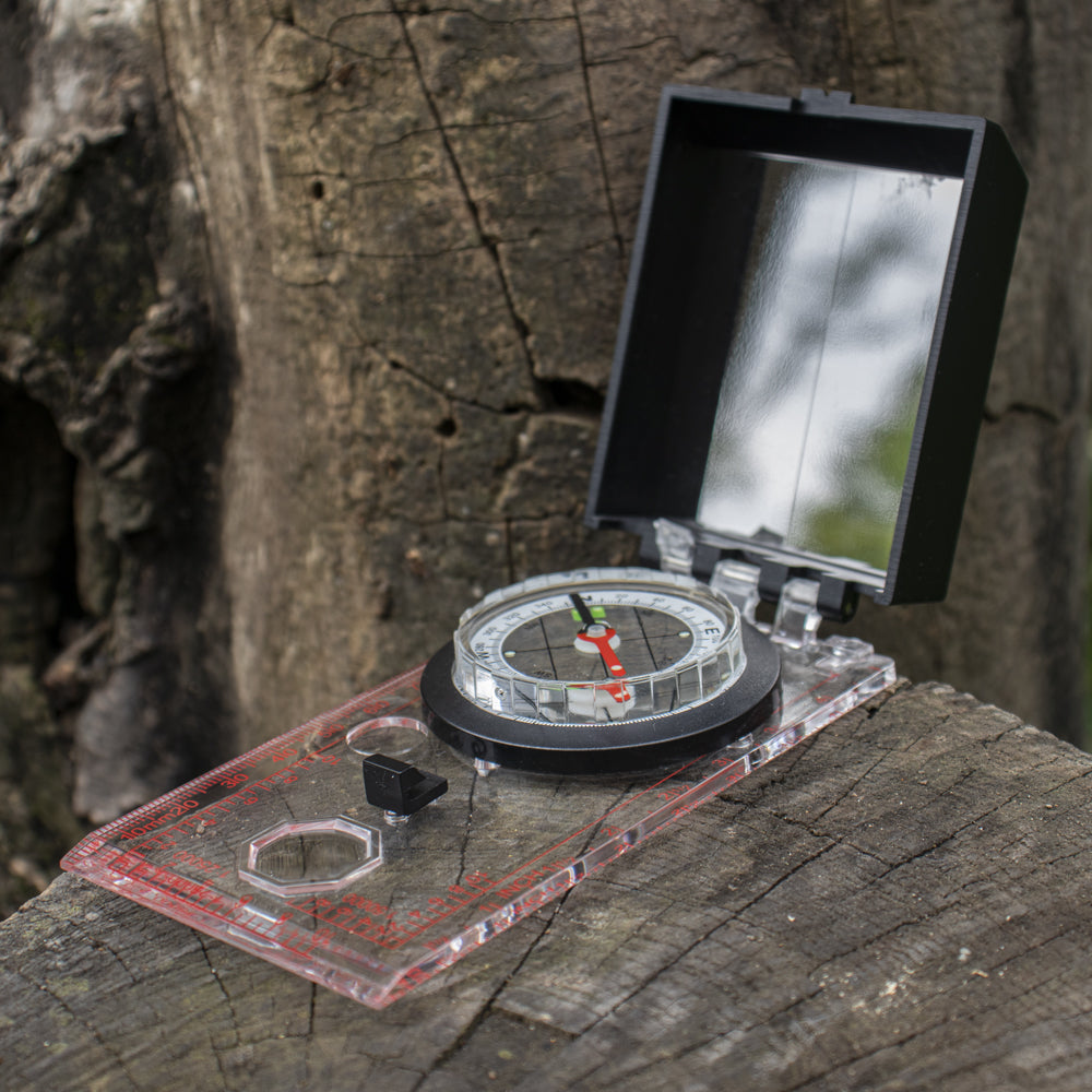 Deluxe Map Compass open on a tree trunk.