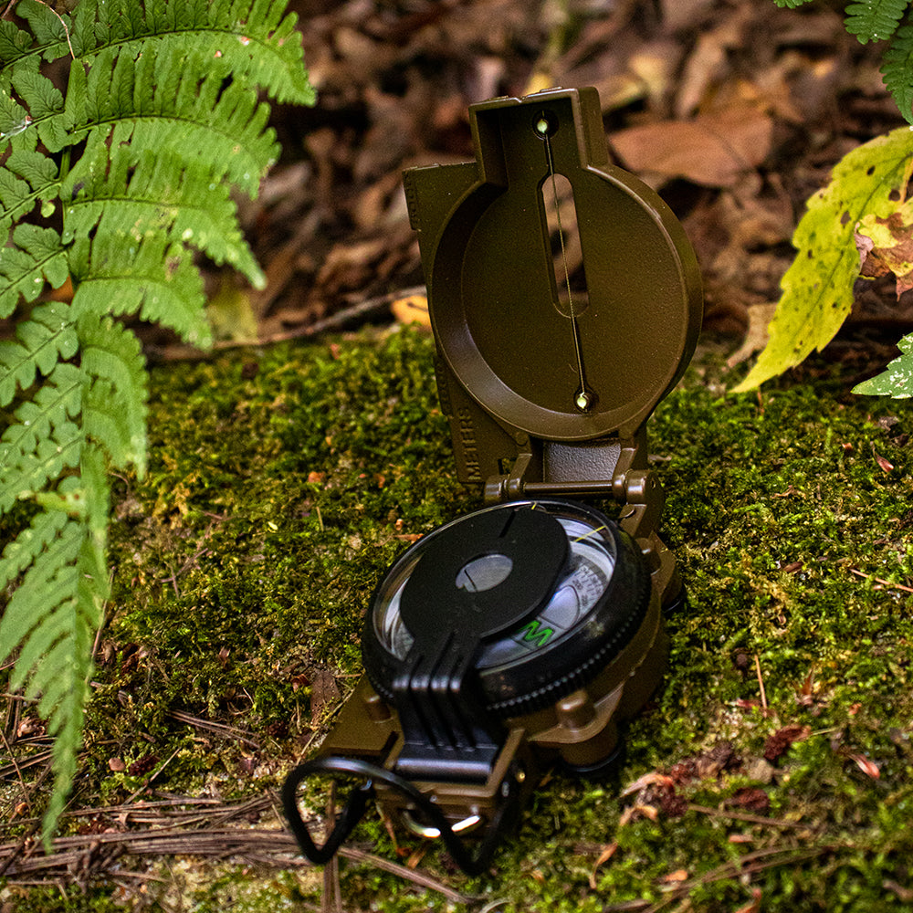 Military Marching Compass open on a bed of moss.