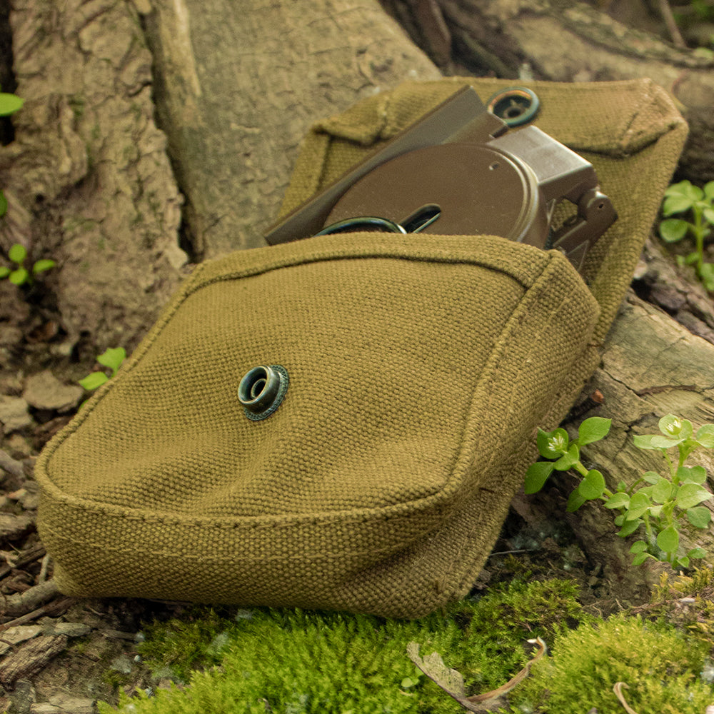 Canvas Compass Pouch laying open on a tree root with a compass inside.