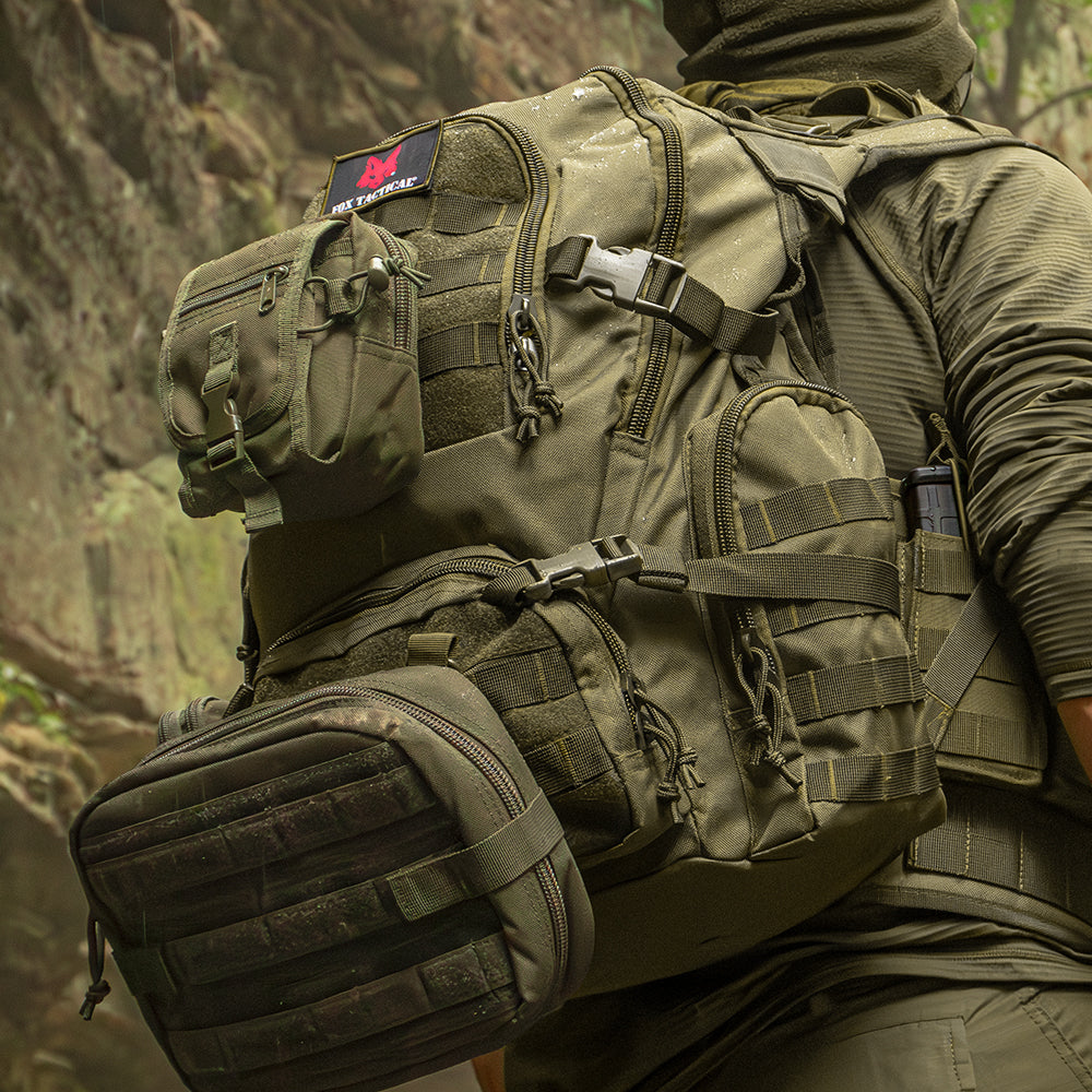 Field Operator's Action Pack on a person wearing tactical gear in a rainy, rocky canyon. The backpack has two modular pouches attached to it.