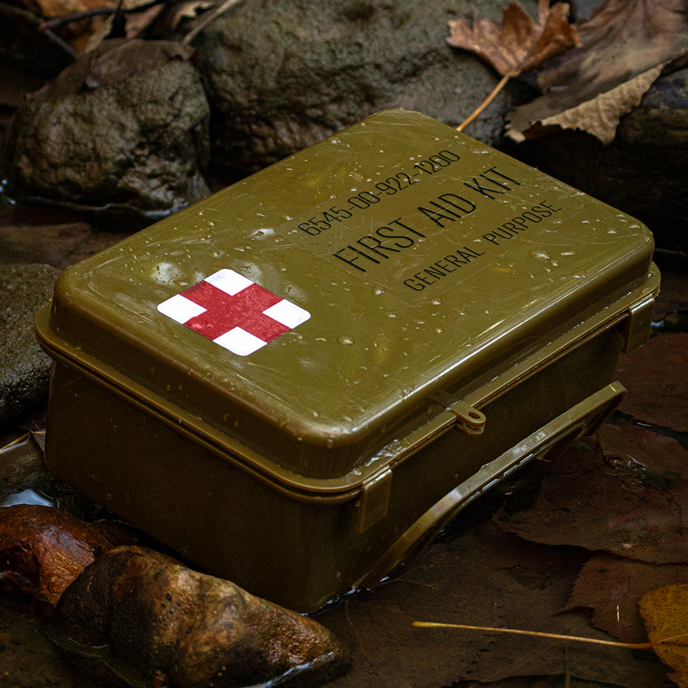 Military General Purpose First Aid Kit all wet laying in a small, rocky creek. 
