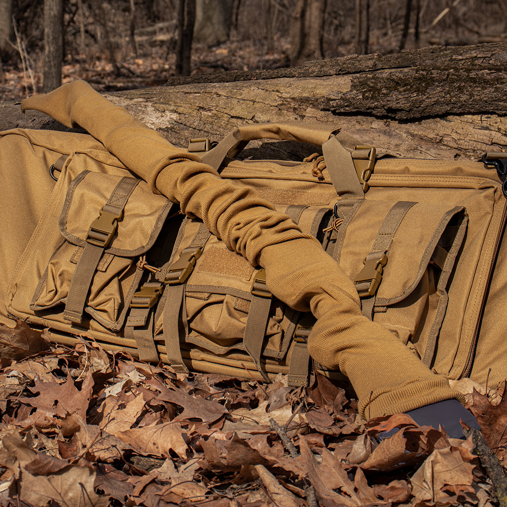 Gun sock laying on a combat case in the woods with fallen leaves surrounding it. 