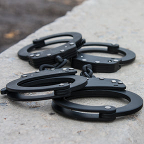 Two pairs of Professional Double-Lock Handcuffs on a parking block.
