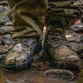 Wet and muddy Vietnam Jungle Boots being worn by a person standing in shallow water.