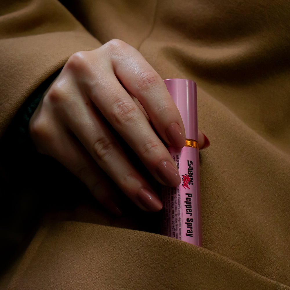 Woman pulling out Sabre® Red Concealable Lipstick from a coat pocket.
