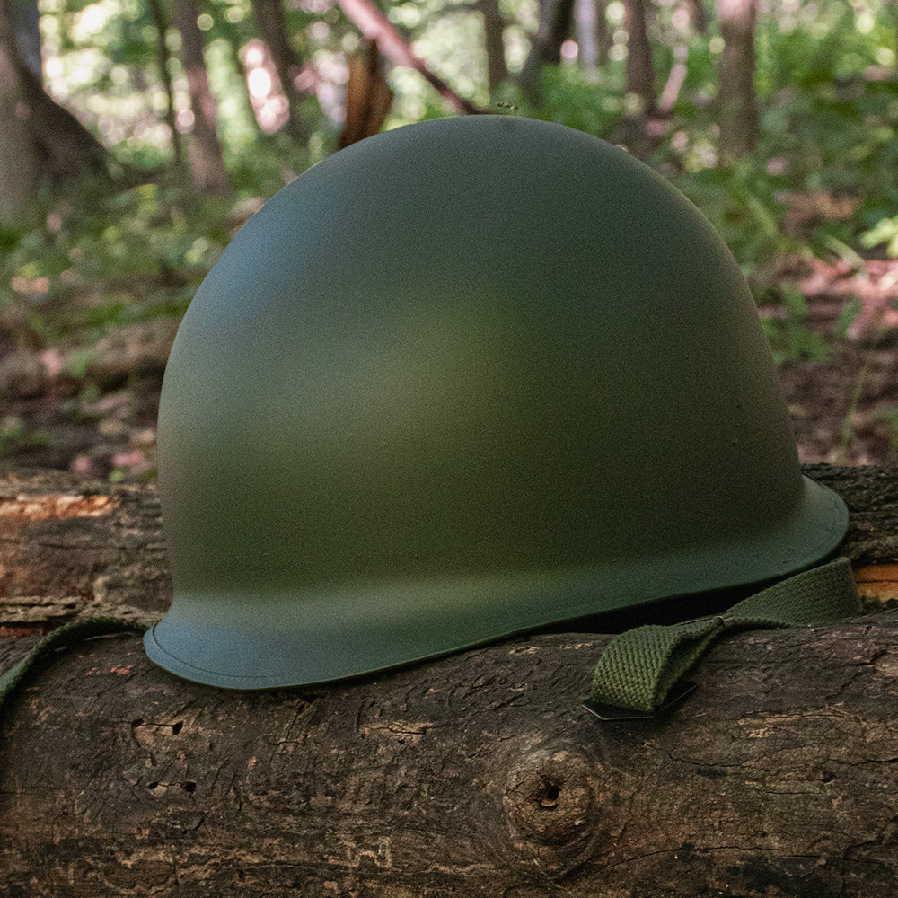 Deluxe M1 Style Steel Combat Helmet on top of a fallen tree.