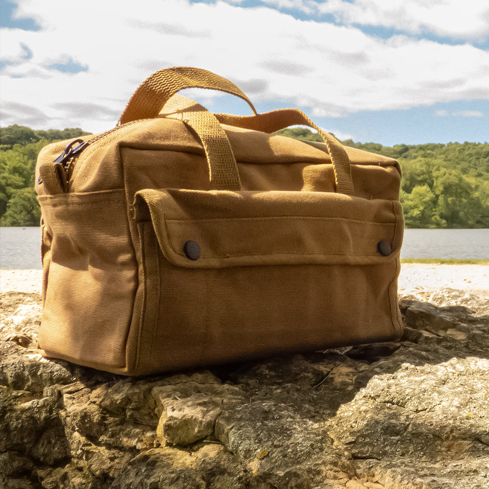 Mechanic's Tool Bag with Brass Zipper on a rock in front of a lake on a sunny day.