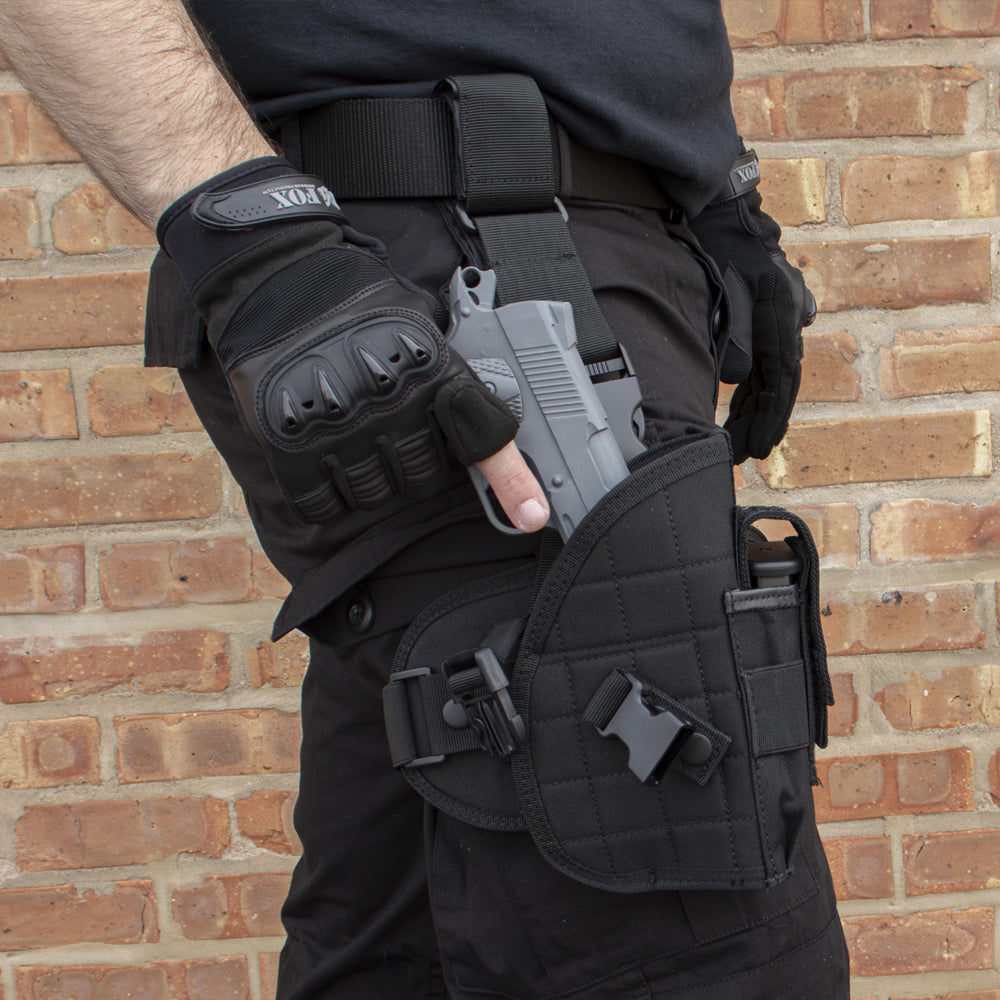 Man wearing a Mission Ready Drop Leg Holster pulling out a pistol in front of a brick wall.