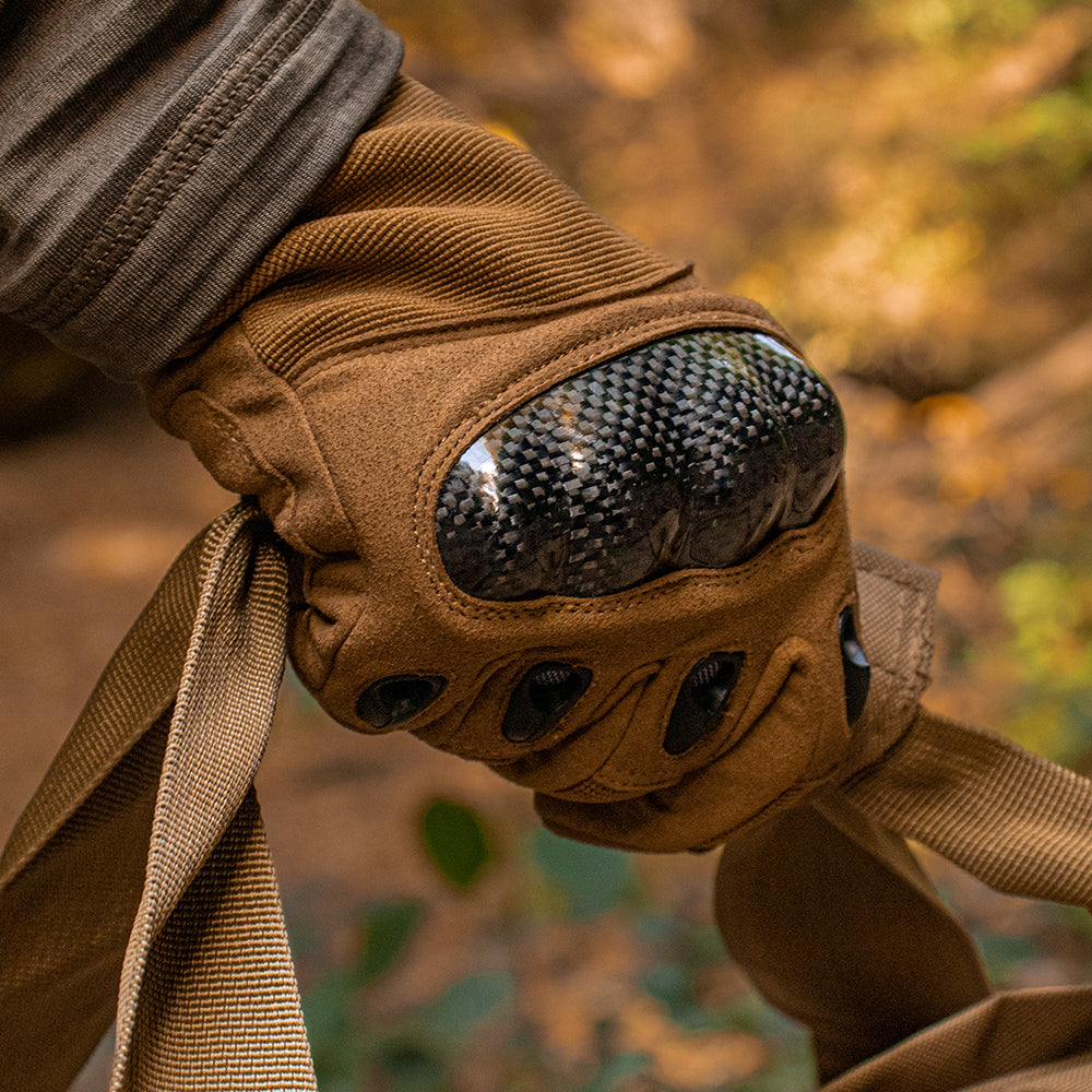 Close-up of Tactical Assault Glove carrying a tactical bag outside in the woods.