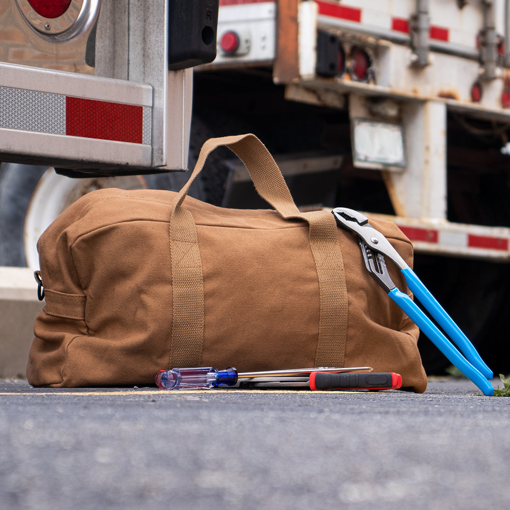 Tanker's Tool Bag surrounded by tools behind two semi-trucks.