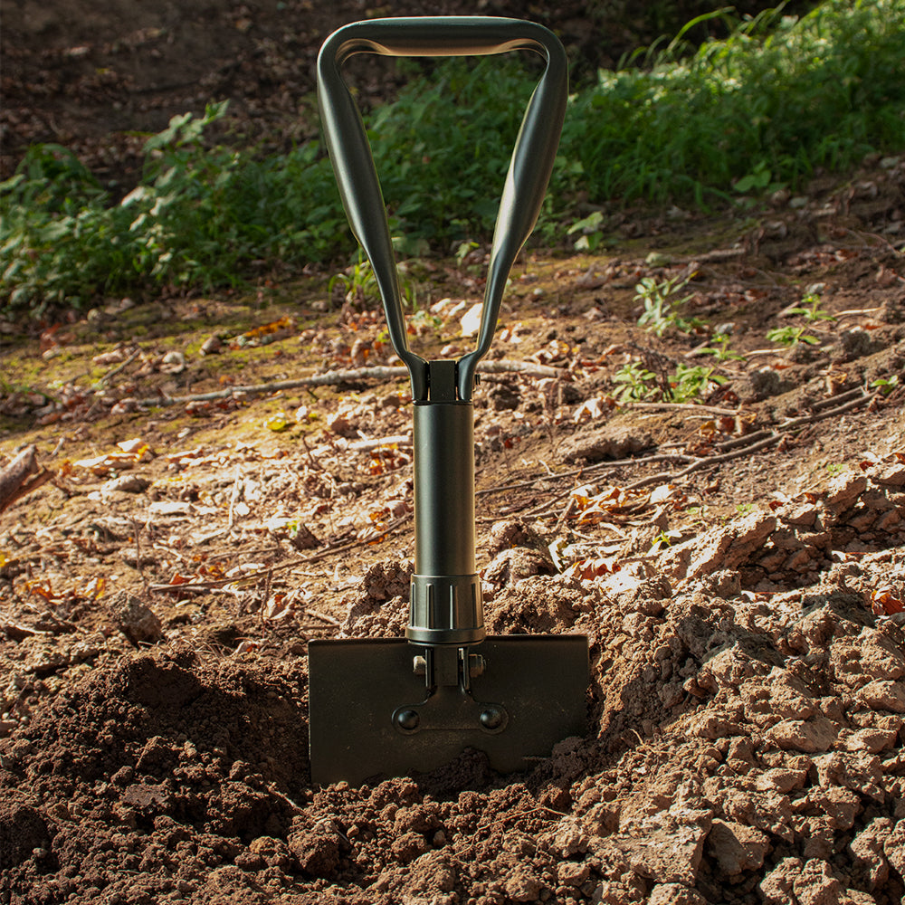 Trifold Shovel stuck in the dirt on a sunny day.