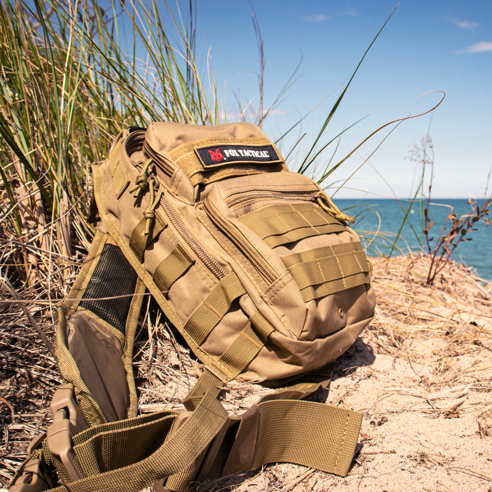 Stinger Sling Pack laying on long grass on the beach. 