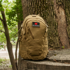 Scout Tactical Day Pack on a stump in front of a tree in the woods.