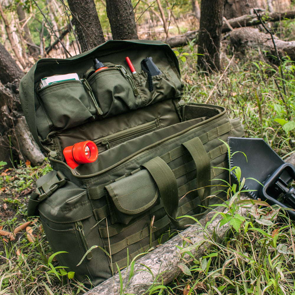 Deluxe Modular Gear Bag in the woods opened up with a plethora of items inside the pockets. 