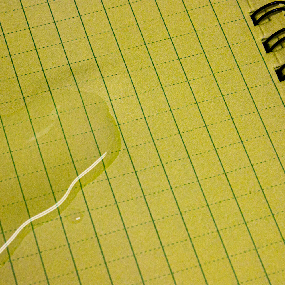 Closeup of water pooled on a page inside a Military Style Weatherproof Notebook. 