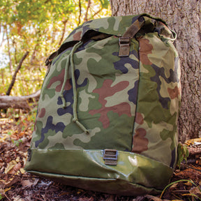 Polish M93 Camo Rucksack lying against a tree in the woods.
