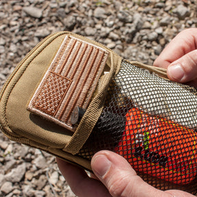 Closeup of a person holding a Tactical Wallet/Organizer with contents shown inside of the front mesh pocket.
